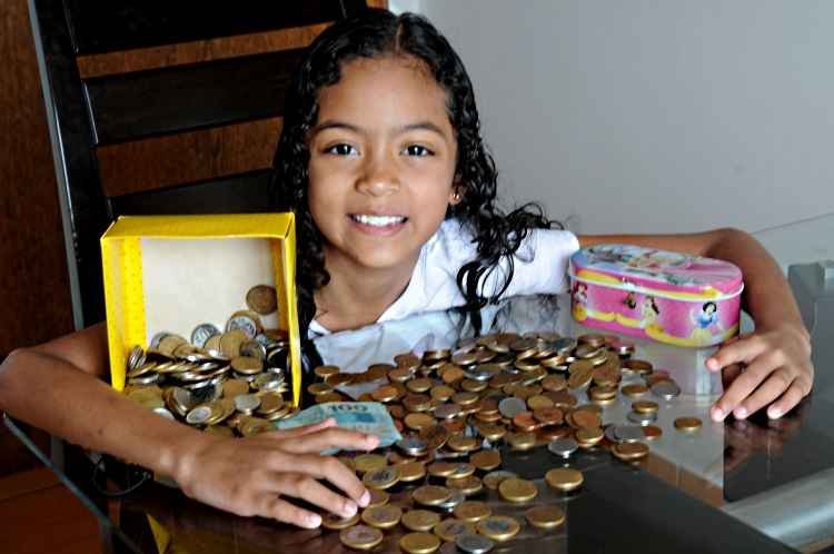 Criança aprendendo a poupar com cofrinhos coloridos, simbolizando educação financeira prática